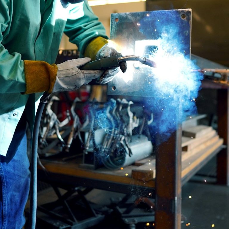 A welder using a welding torch, creating bright sparks and blue light.