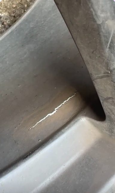Alloy wheel with a large crack Close-up of a scratched surface on a metallic object.