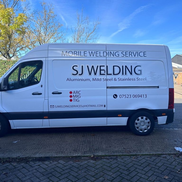 White van with "SJ Welding" and service details on the side. Clear blue sky in background.