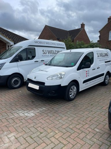 SJ Welding Mobile services vehicles Two white vans parked in a residential driveway under a cloudy sky.